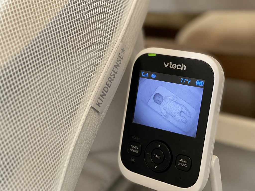 Baby monitor camera angled for clear view through crib tent mesh